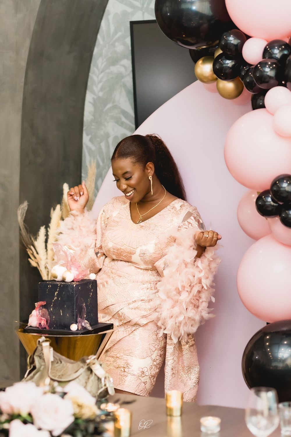 A celebration with pink and black balloon decorations, pampas grass, and a festive party table setup in luxurious style.