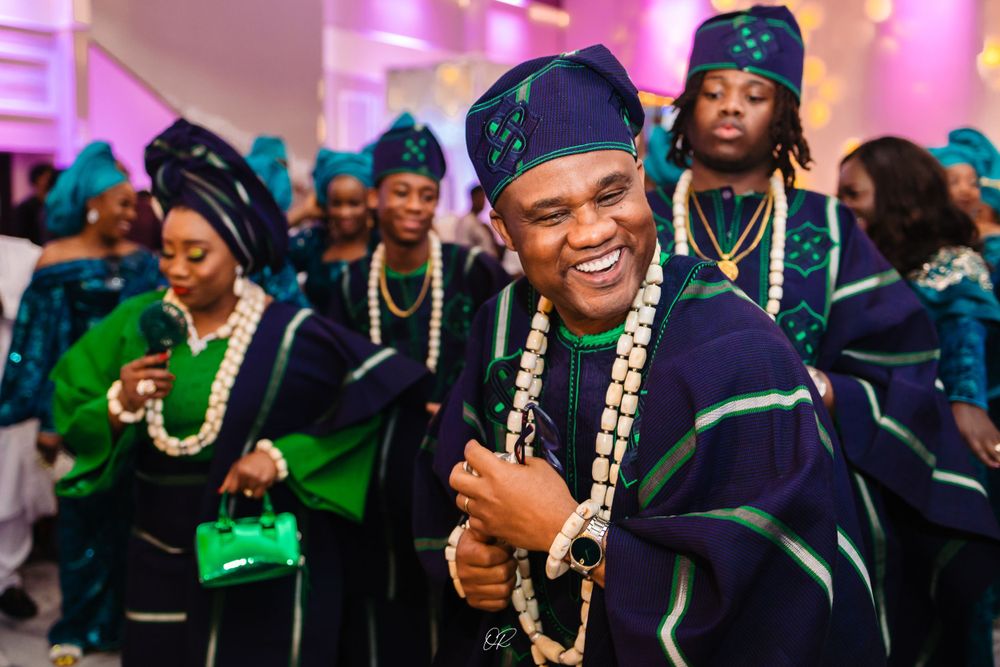People wearing traditional Nigerian navy and green academic regalia celebrate during a graduation ceremony.