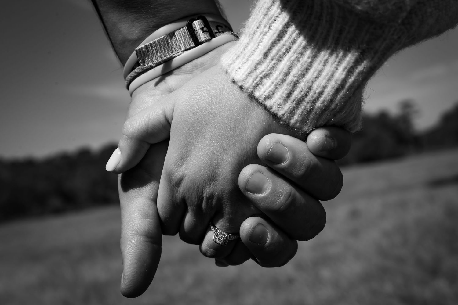 Two hands clasped together in an intimate close-up black and white photograph.