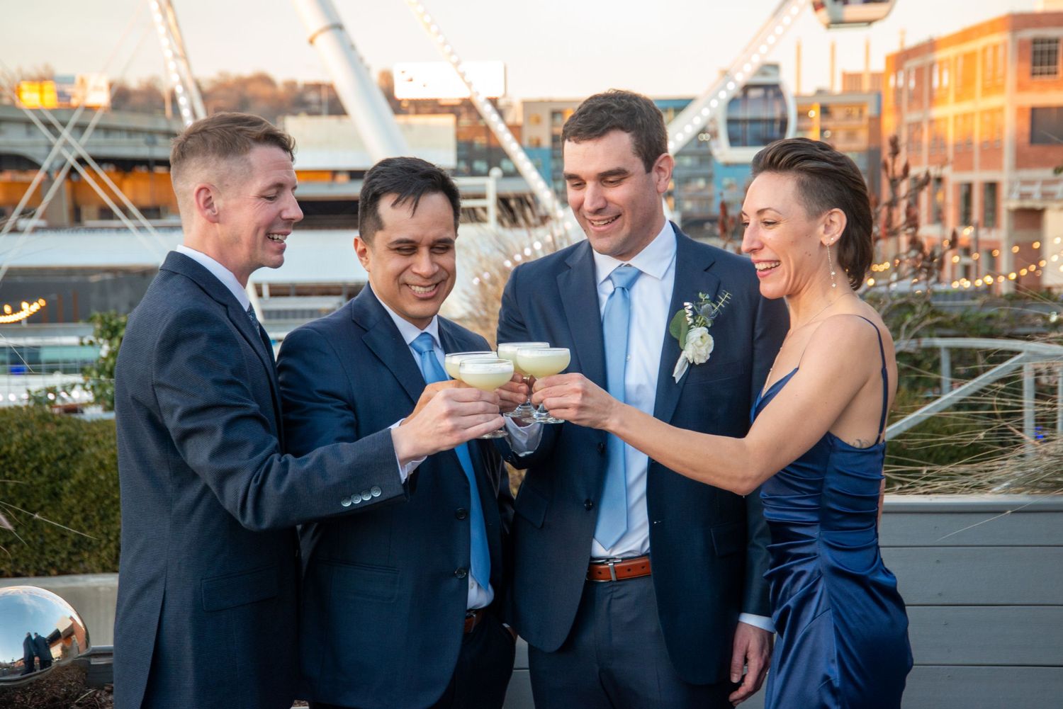Wedding party members toasting with champagne glasses on an outdoor patio at sunset.