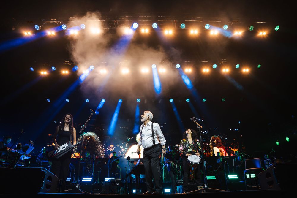 Wide concert stage view with blue and white spotlights creating an atmospheric light show.