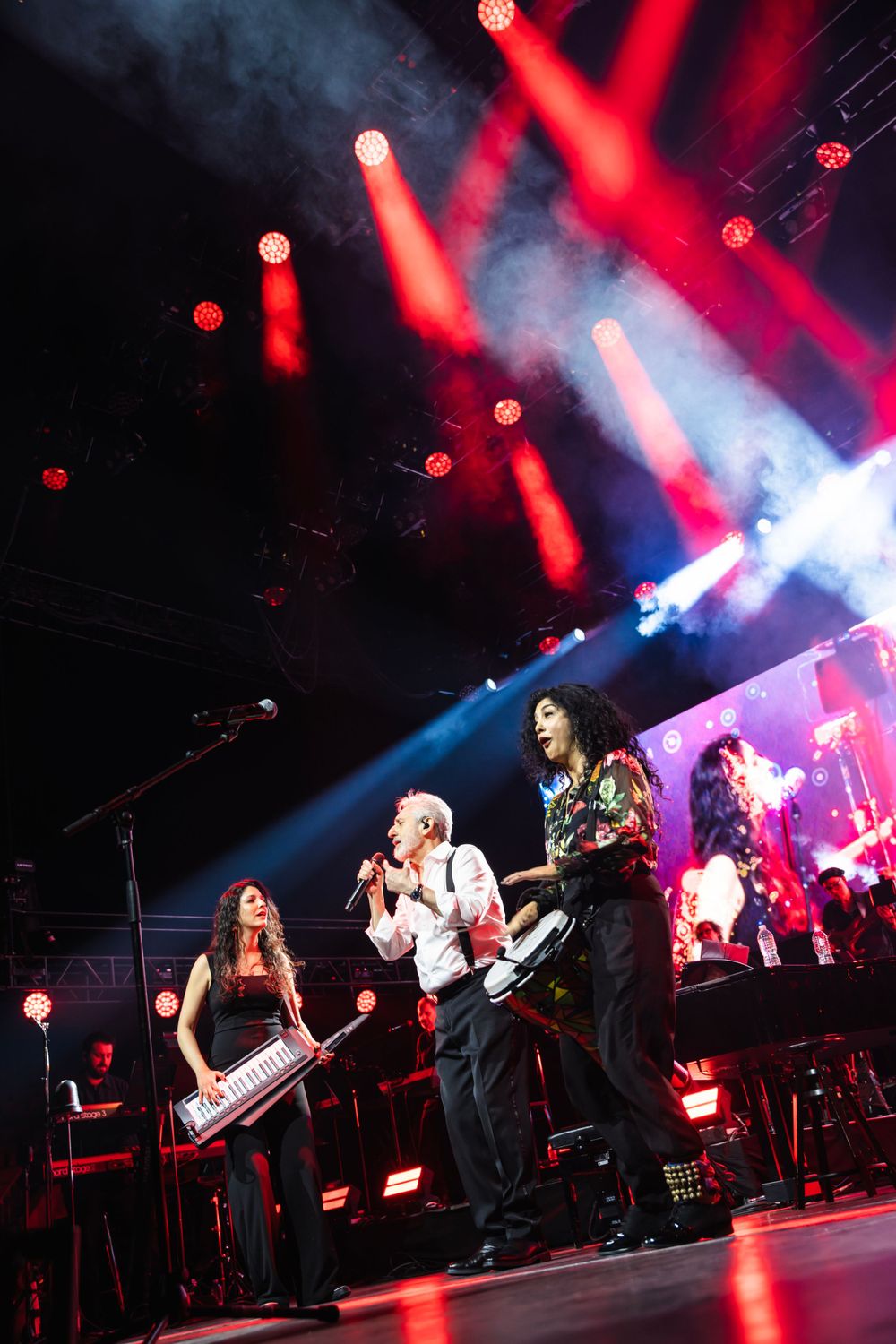 Rock band performing on stage with dramatic red and blue lighting effects.
