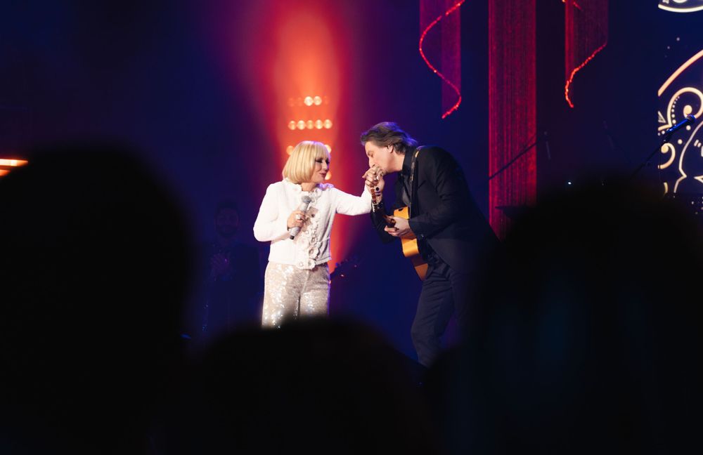 Concert performers on stage with dramatic red lighting and fog effects during a live show.