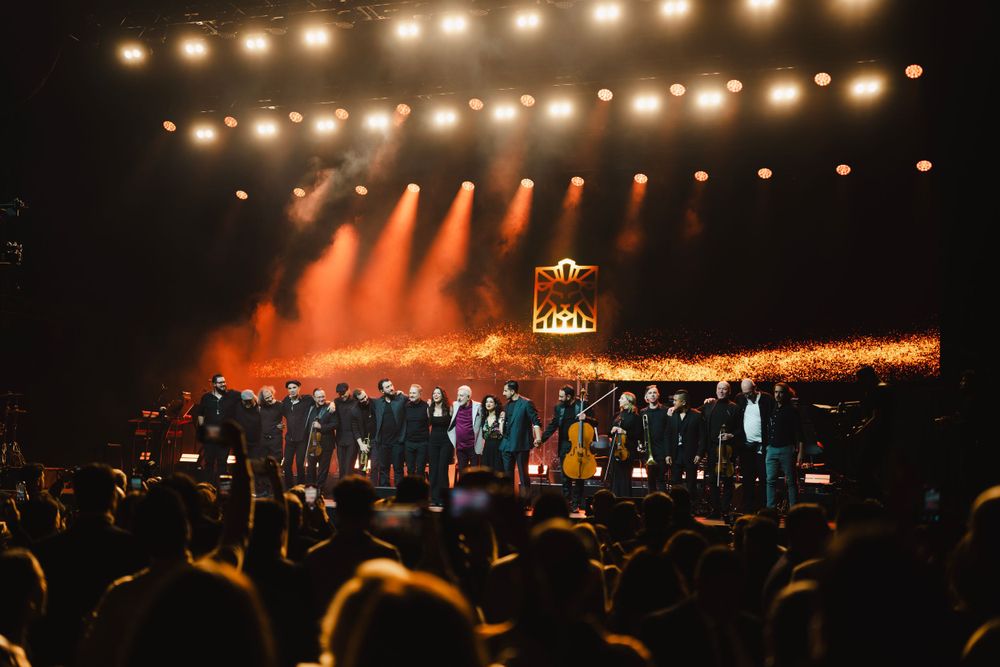 Concert venue illuminated with warm amber stage lights creating a panoramic glow across the arena.