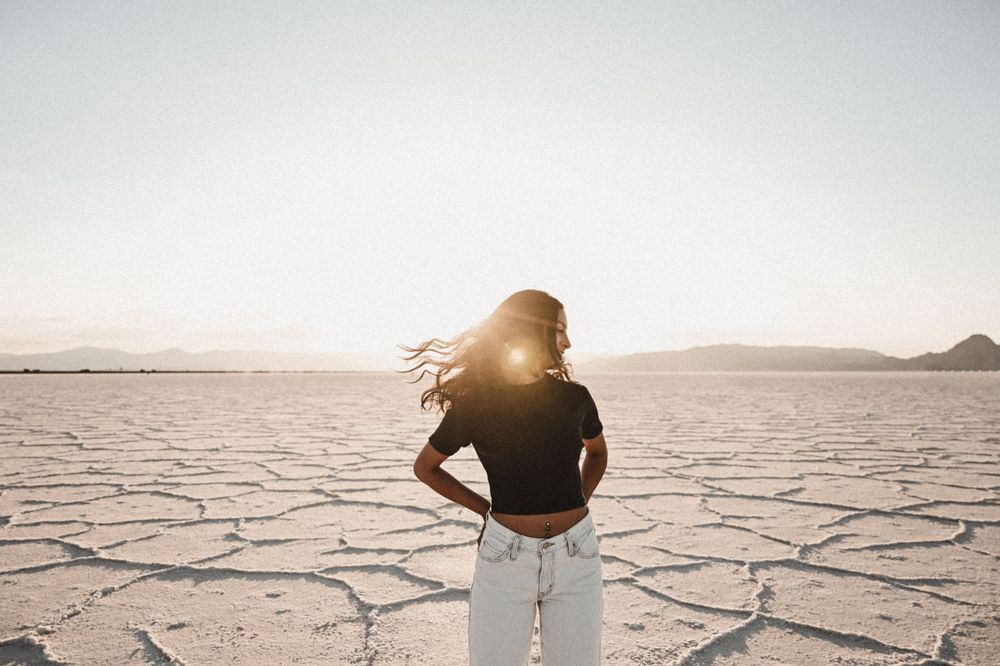 Person walks along vast salt flats during golden hour.