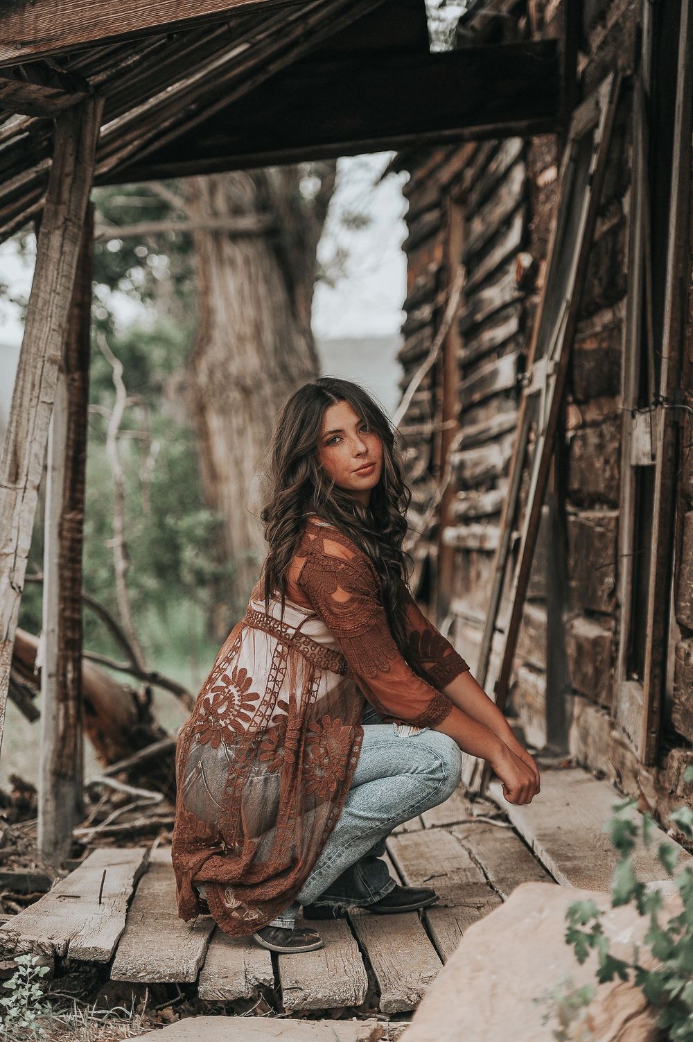 Artistic portrait session at rustic wooden structure with vintage aesthetic.