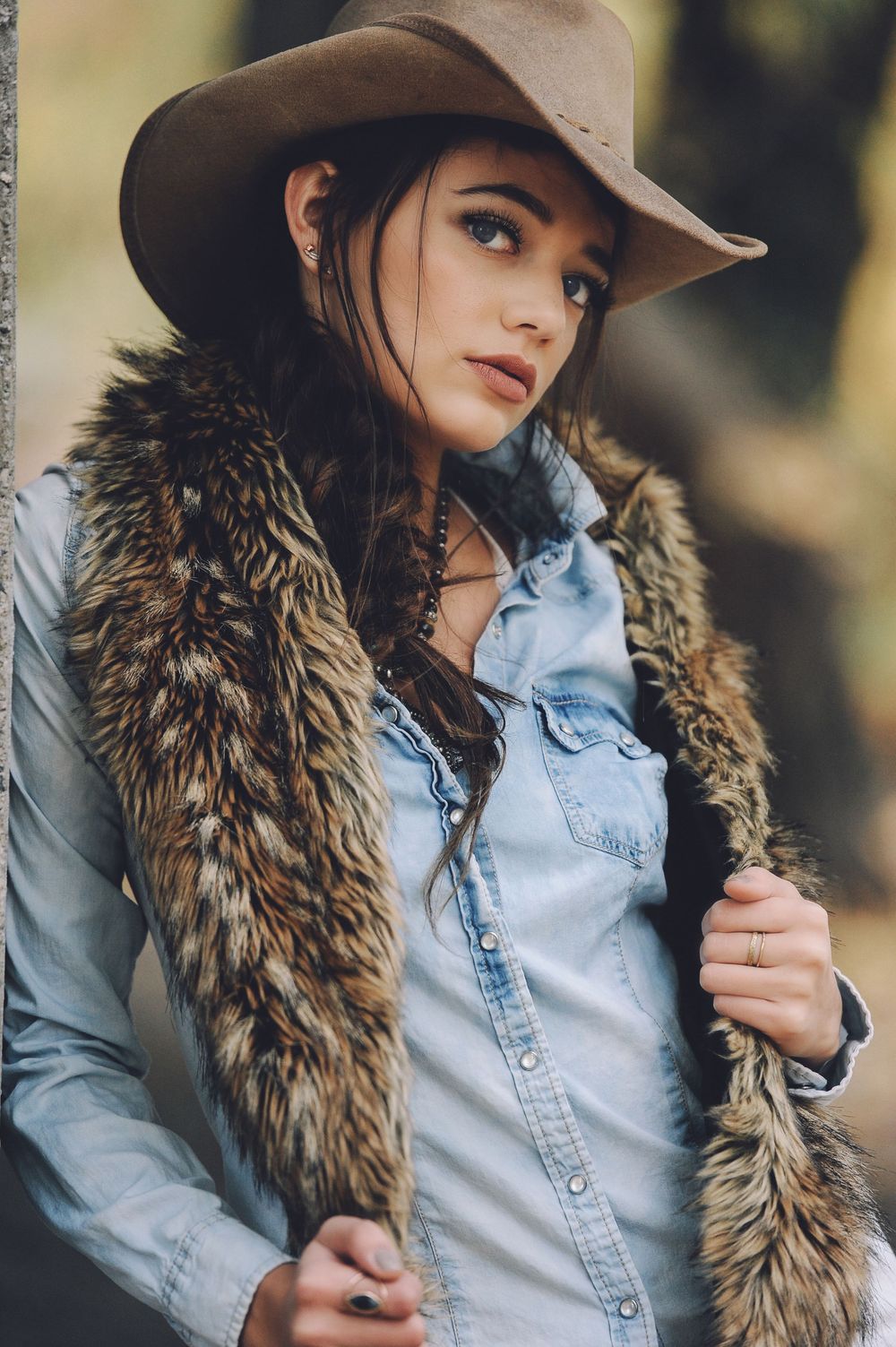 Western-inspired look with fur collar, denim shirt and neutral hat.