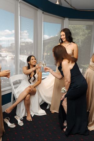 Person in white dress getting assistance with shoes in a room with large windows.