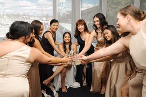 Wedding party guests clink champagne glasses together in a celebratory toast at a reception.