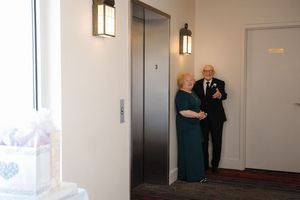 Directory or hallway navigation sign with room numbers and arrows mounted on a white wall.