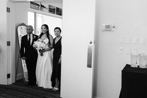 Wedding party waiting anxiously in a hallway while others peek around the corner before a ceremony.