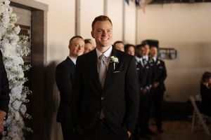 A group in formal black suits and ties stand together at a formal event with elegant white floral decor.