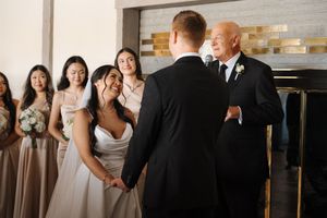 Wedding party laughing and posing together in front of white brick wall.