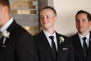 Groomsmen in black suits stand together during a formal wedding celebration.