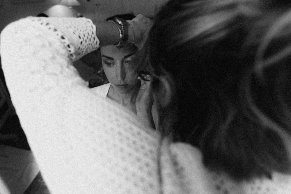 A close-up black and white photograph showing someone applying makeup near a mirror.