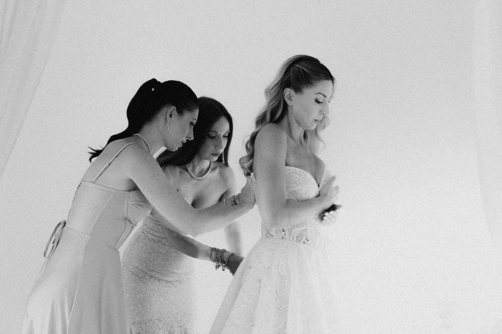 Black and white photo series showing a bride getting ready for her wedding day and getting help with her dress.