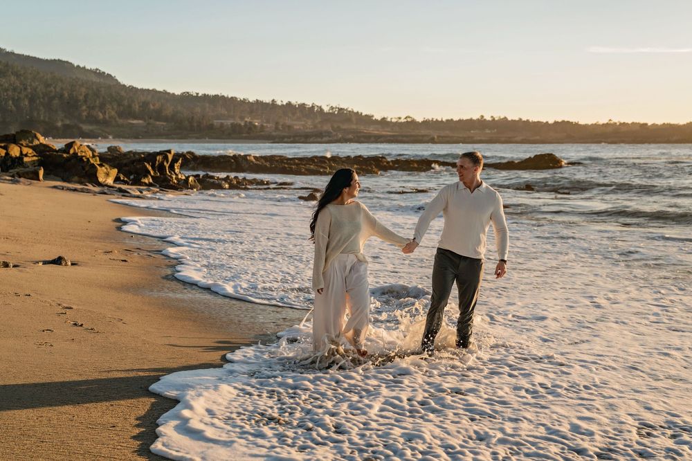 Waves crash onto a sandy beach as couples enjoy a romantic evening by the ocean.