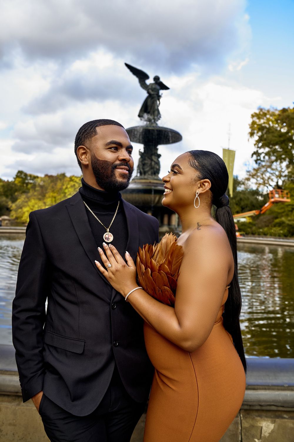 A couple shares a joyful moment by Bethesda Fountain in Central Park during their engagement photo session.