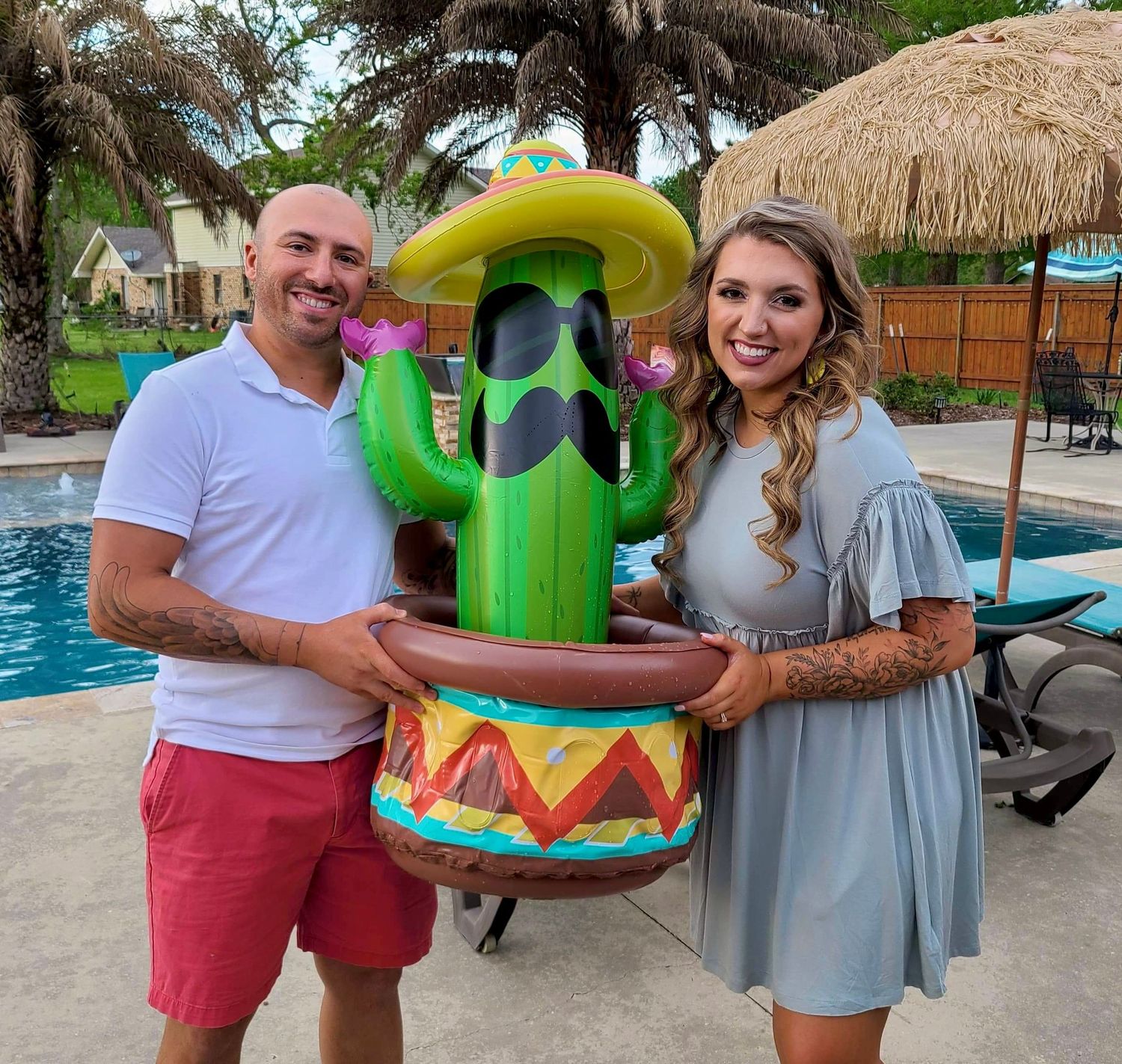 People celebrating at a tropical poolside party with inflatable decorations.