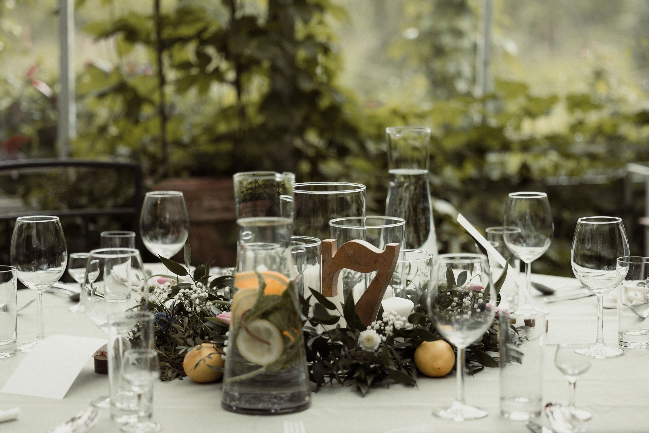 Wine glasses on a rustic table styled with decorative natural elements for an elegant event setting.