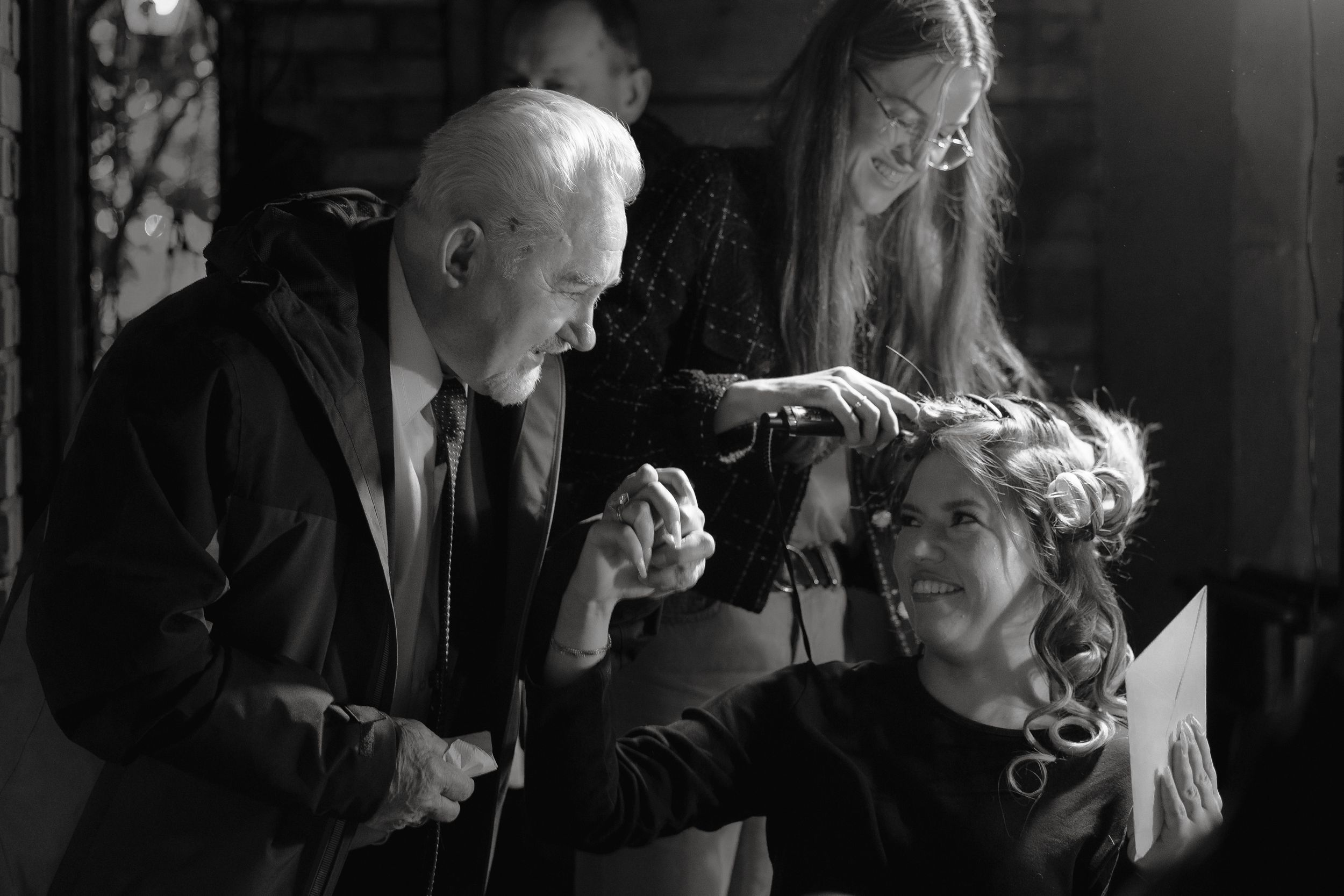 A black and white candid moment captured during an intimate gathering where people interact animatedly.