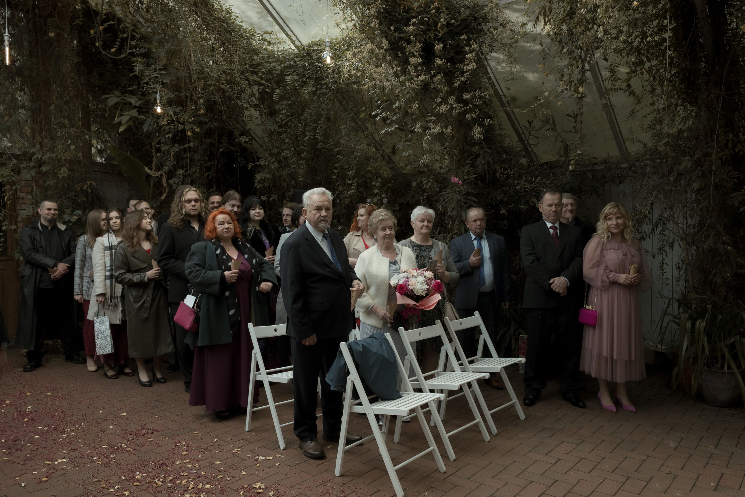 A panning shot showing rows of white chairs set up outdoors at a wedding ceremony among trees and greenery.