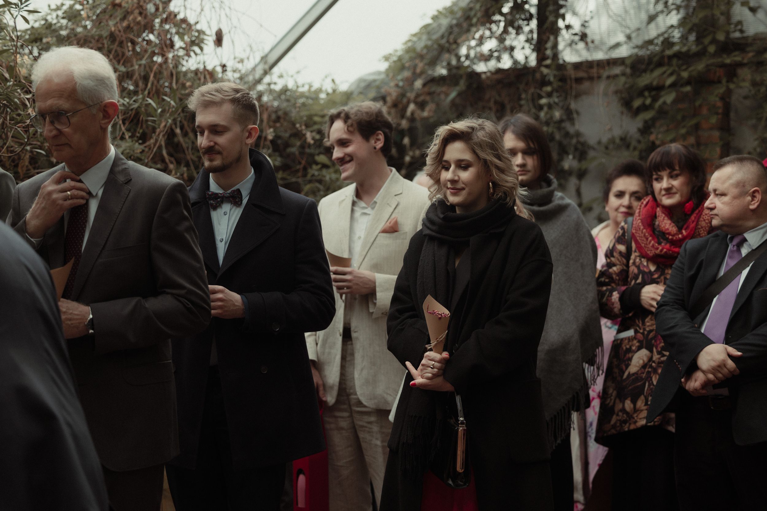 Guests are gathered at an outdoor celebration, engaged in conversation and smiling at different angles.