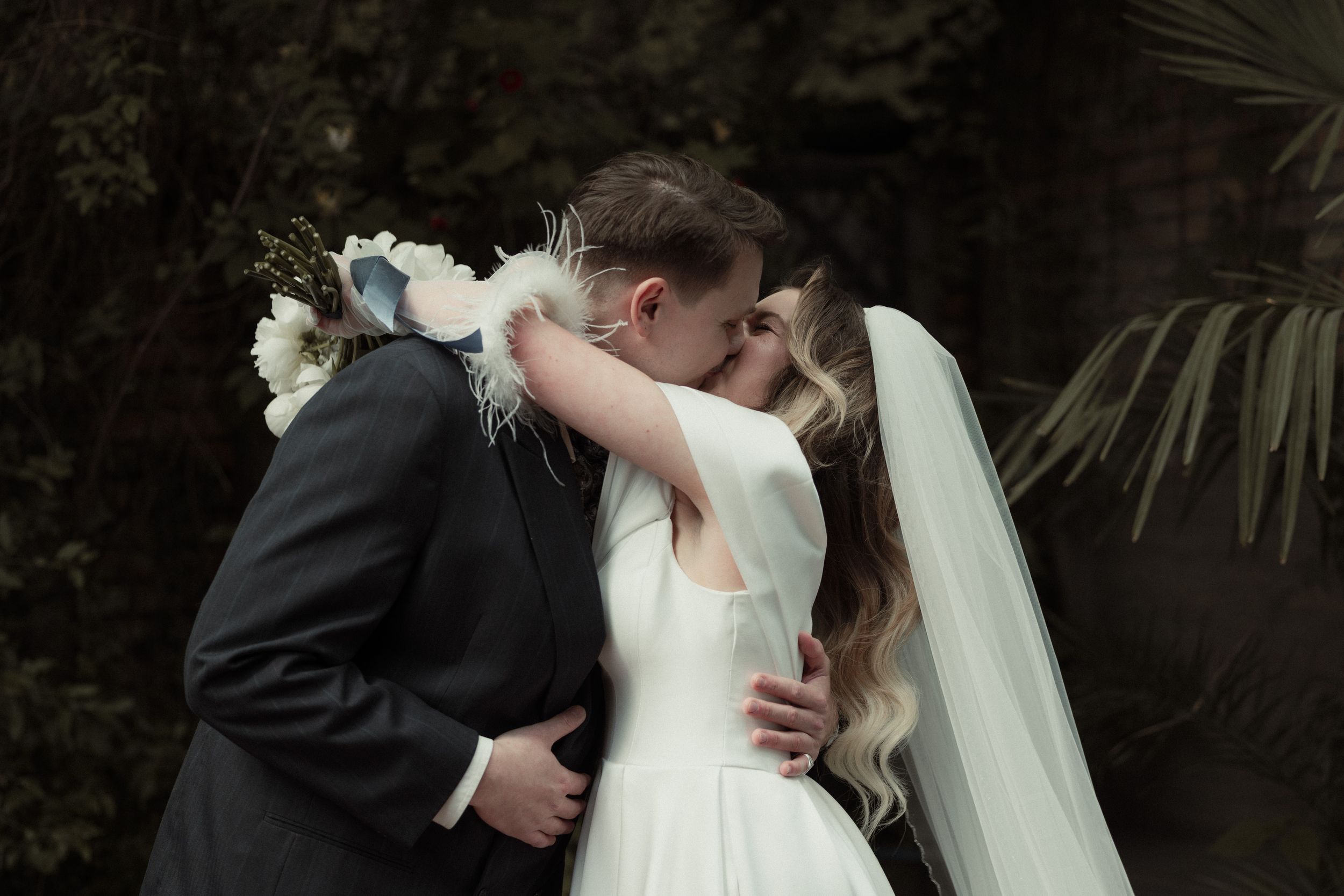 Newlywed couple embraces during their first dance at a romantic garden reception.