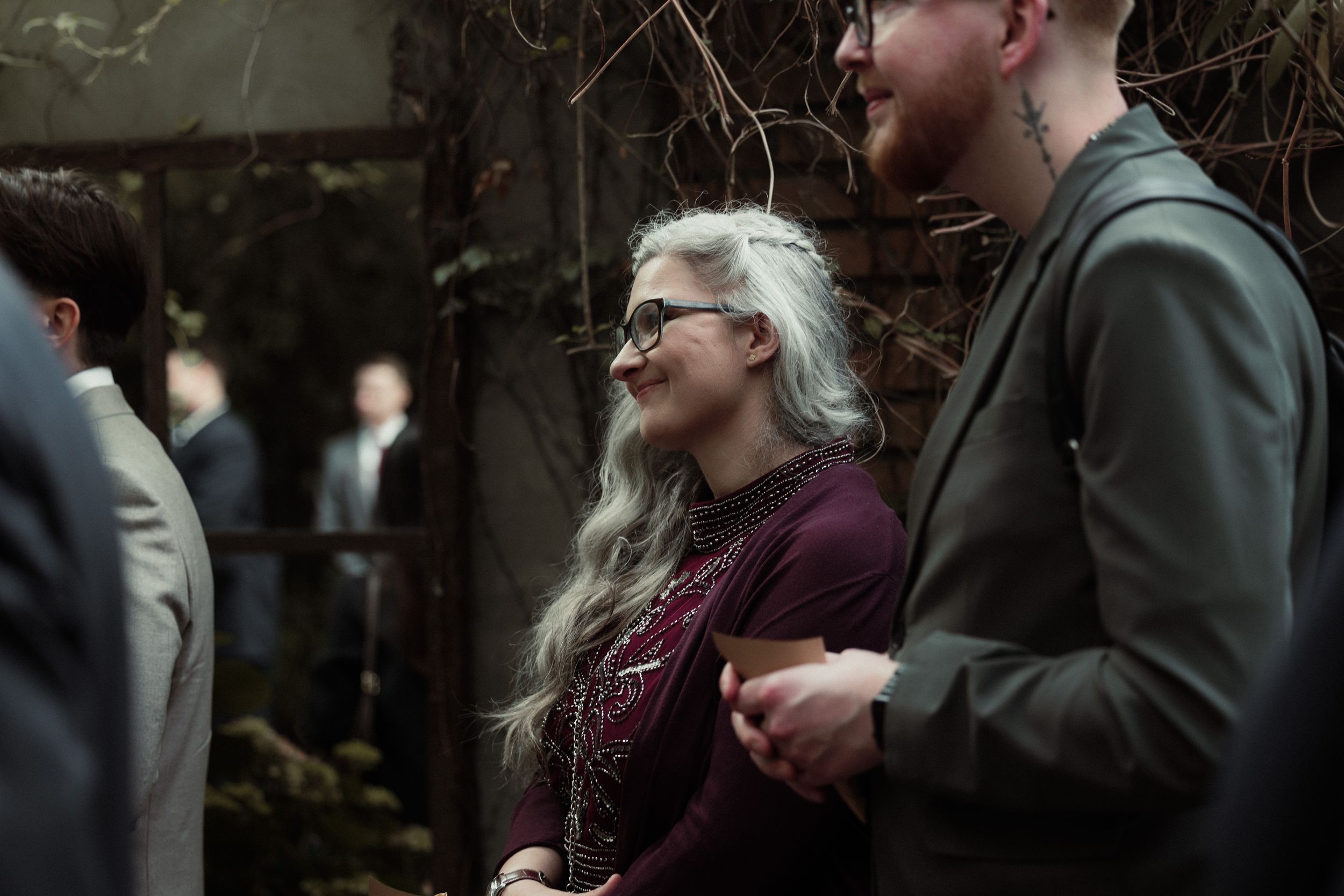 A couple stands close together sharing an intimate moment outdoors in a winter park setting.
