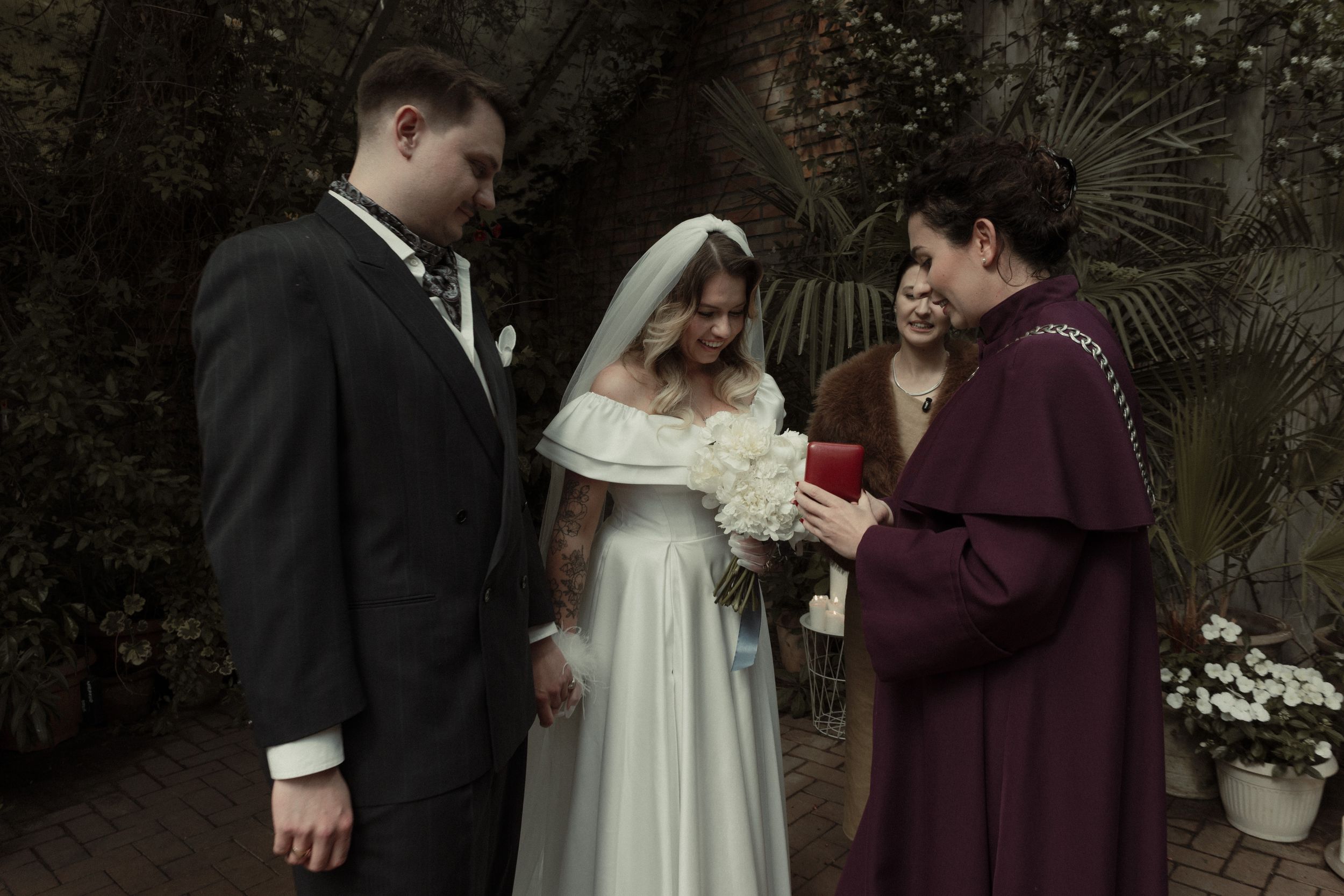 A wedding ceremony takes place outdoors as a couple and officiant read from a book during the service.