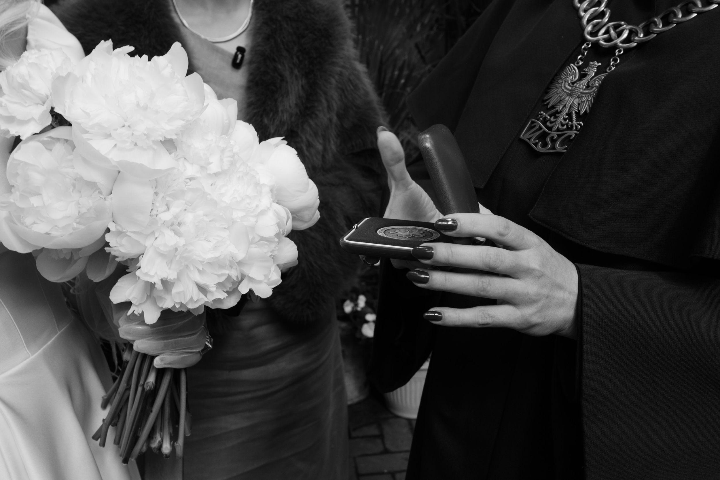 A bride and groom hold their wedding bouquet together in intimate black and white photography.