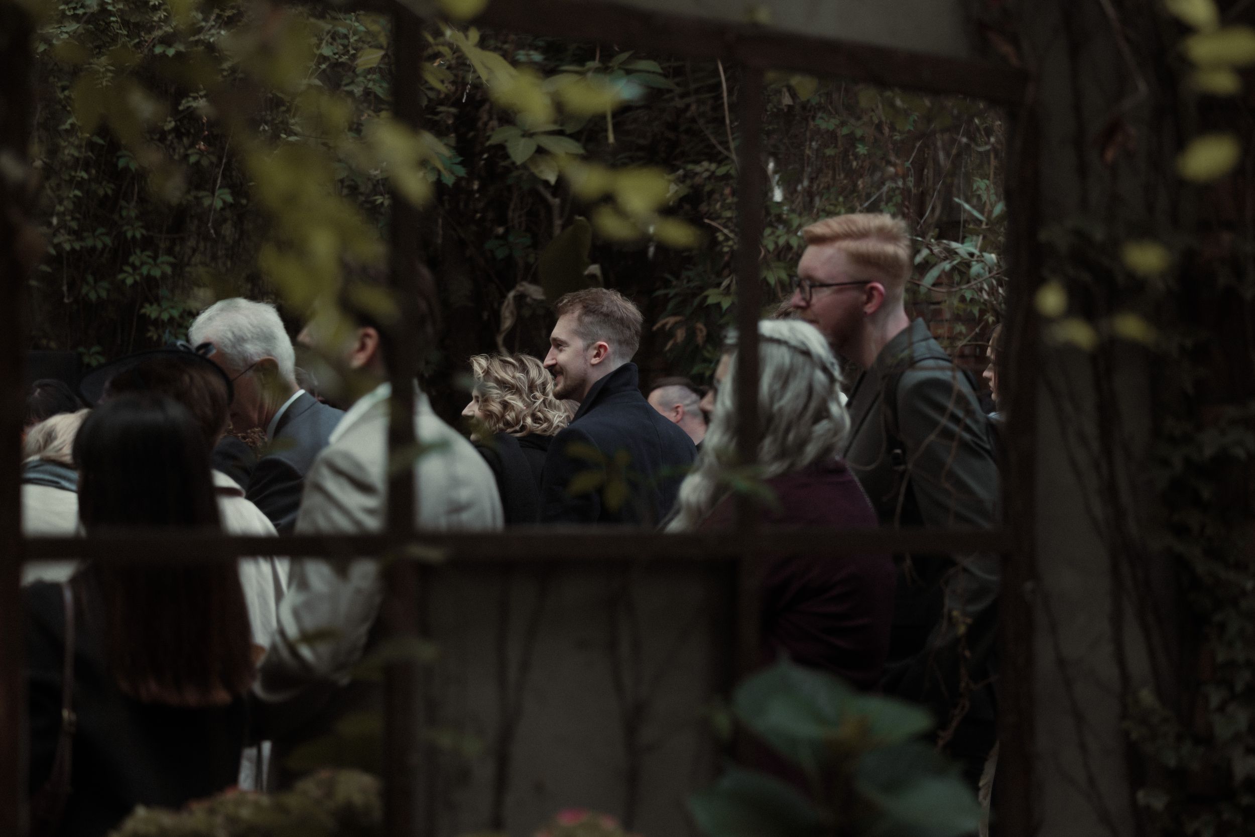 A group of people gathered around an outdoor table for a social gathering at dusk.