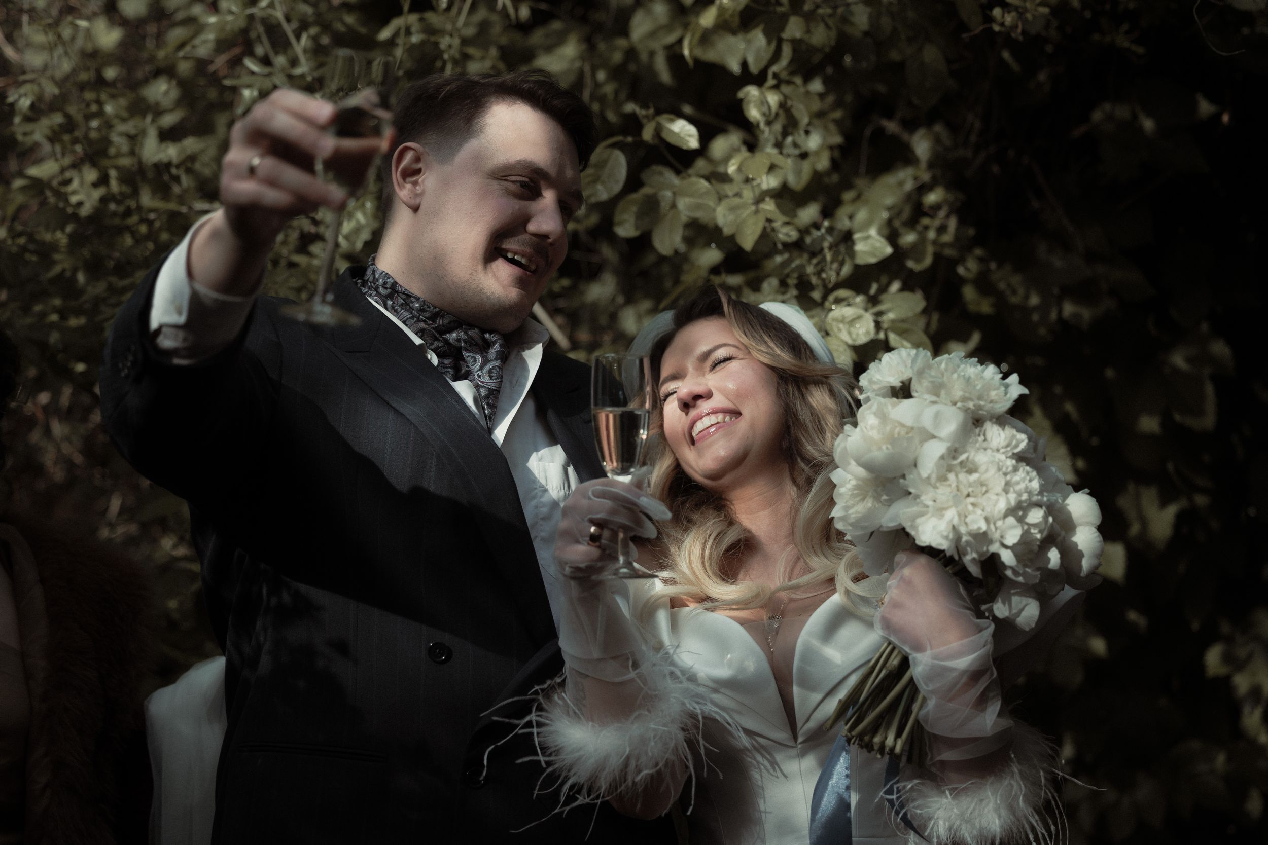 A romantic moment between a couple outdoors among trees and foliage in a natural garden setting.