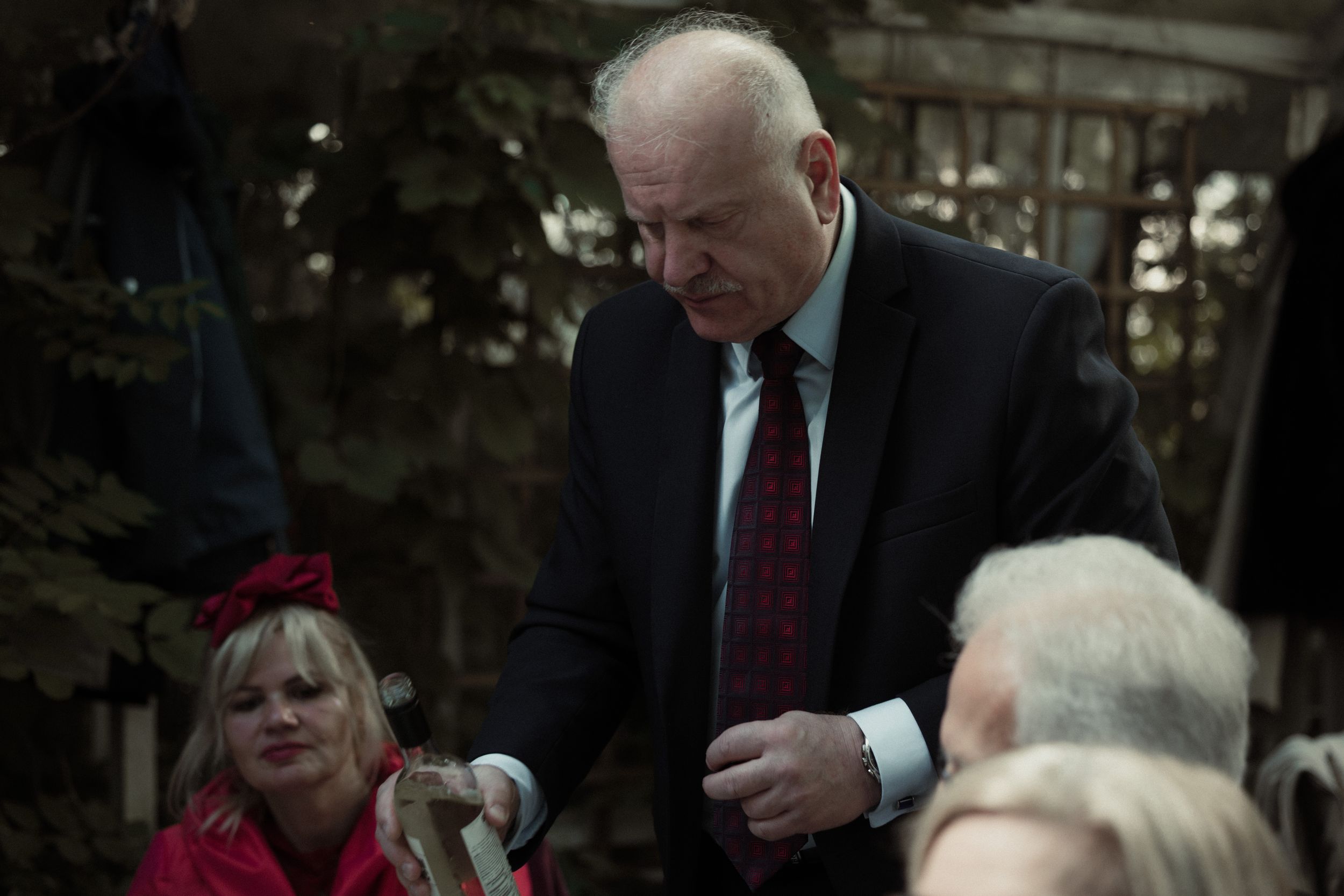People shake hands and gather during a formal ceremony in a dimly lit venue.