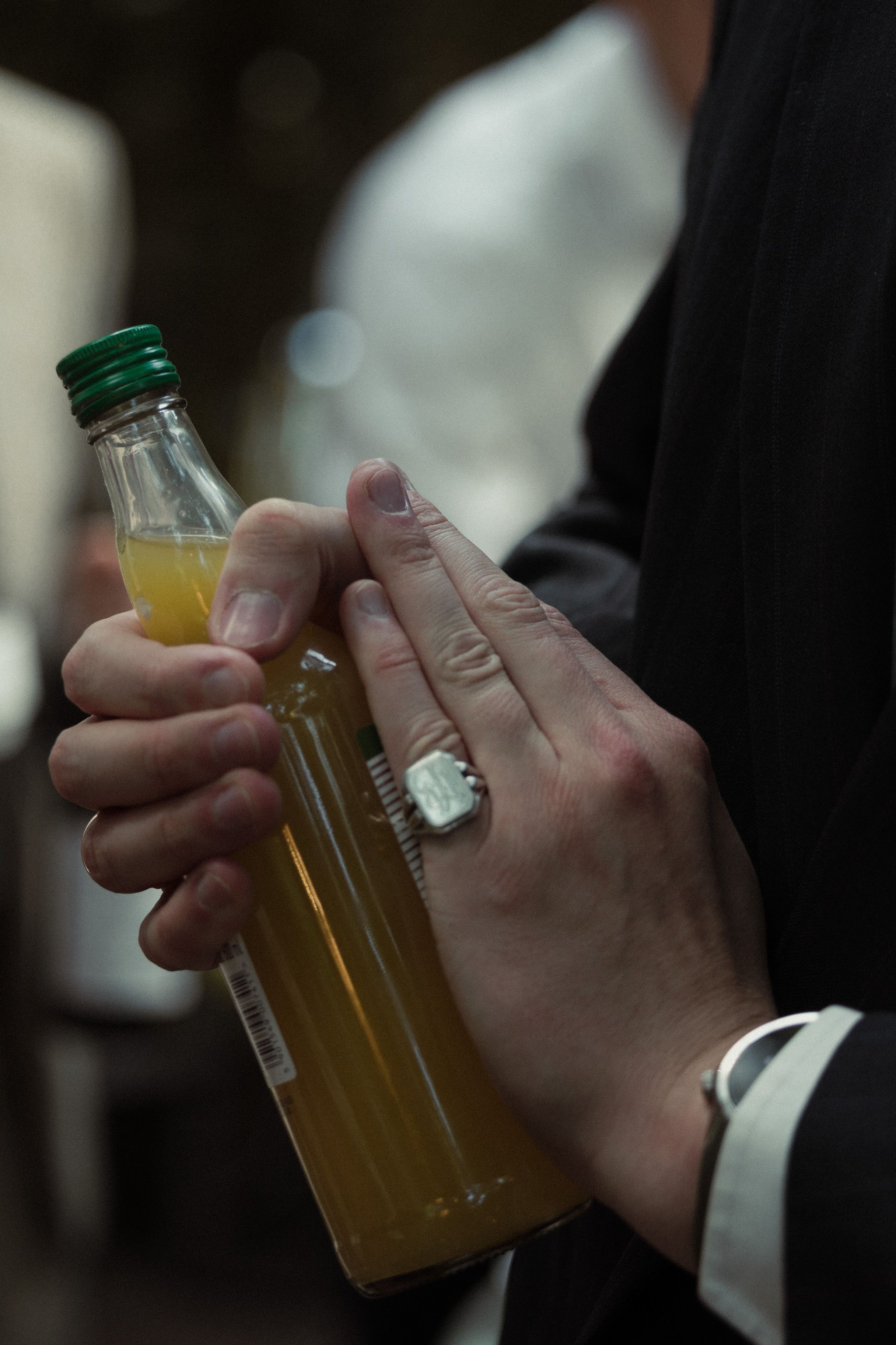 Three hands holding glass bottles of Starbucks beverages in a dark setting.