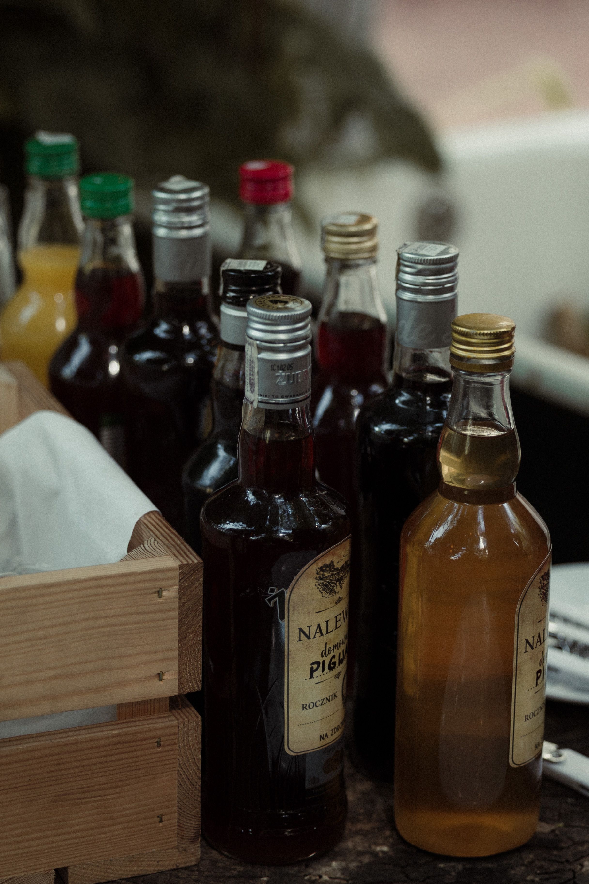 Collection of vintage glass bottles in dark amber and clear colors arranged in wooden crates on a rustic surface.