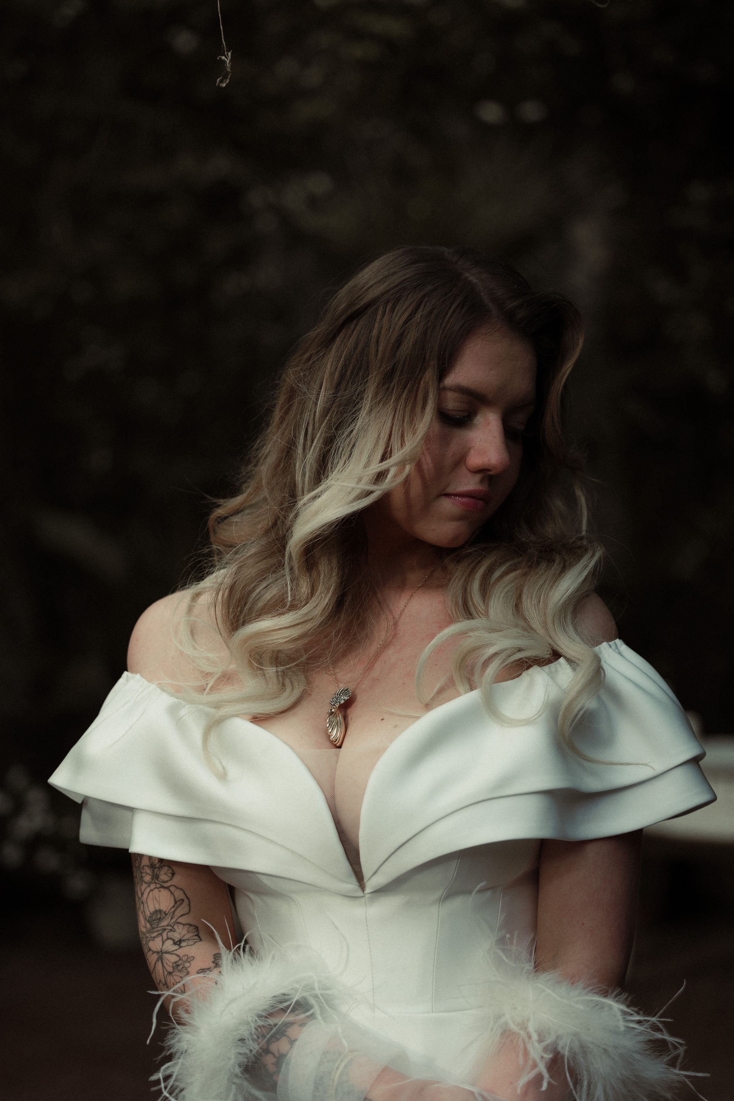 A wedding dress with a dramatic off-shoulder neckline and feather details shown in a series of close-up shots.