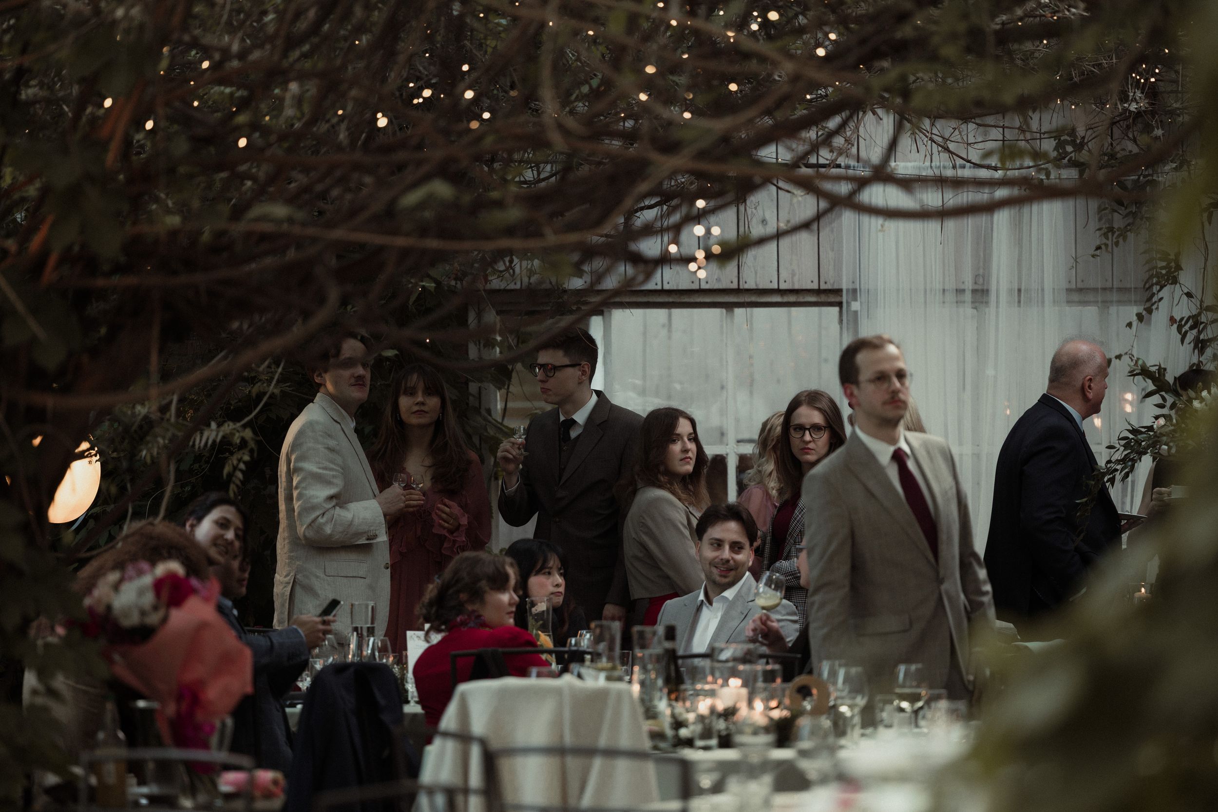 An elegant outdoor wedding reception setup with tables under string lights in a garden setting.