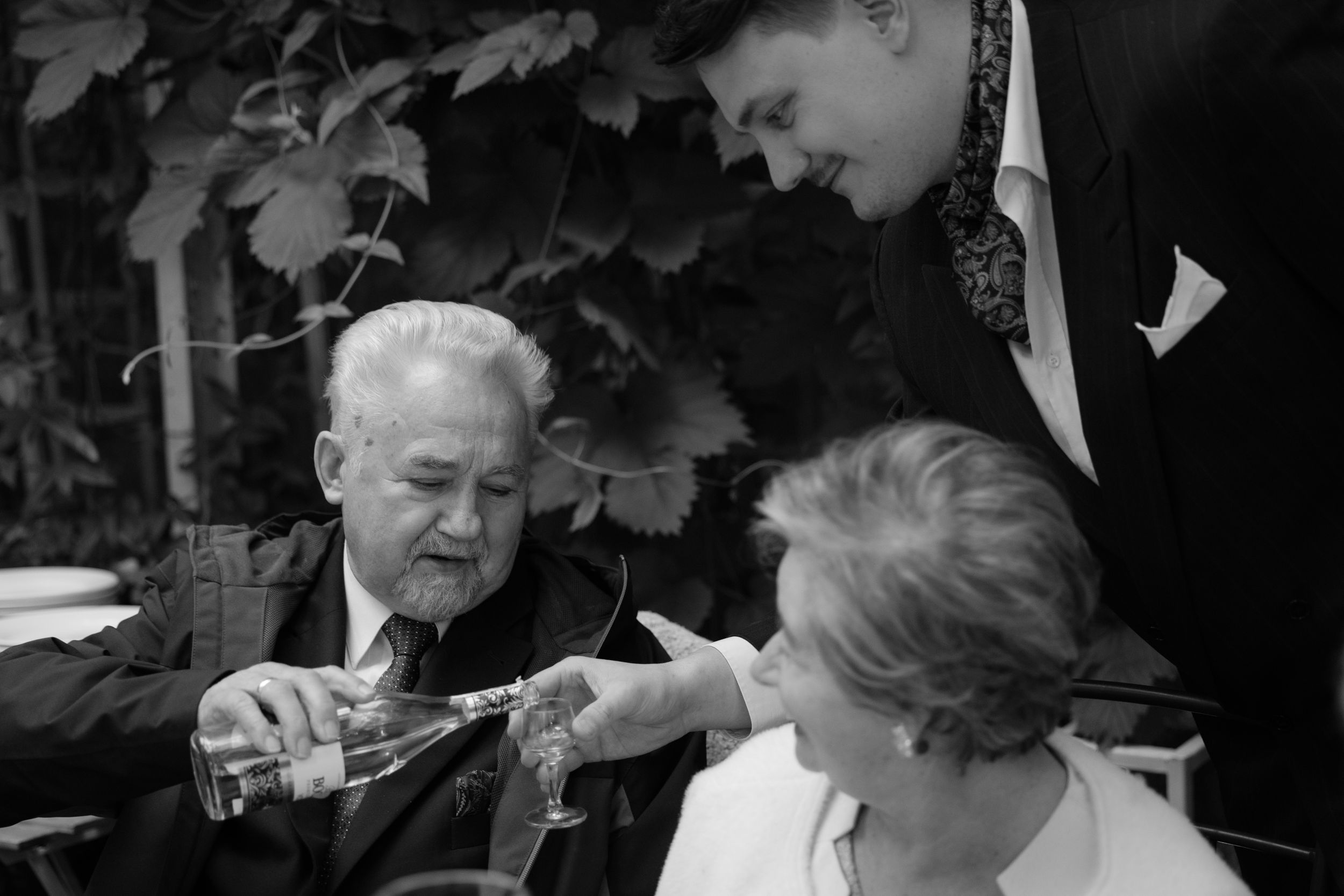 A collection of black and white wedding photos shows romantic outdoor moments between newlyweds under foliage.