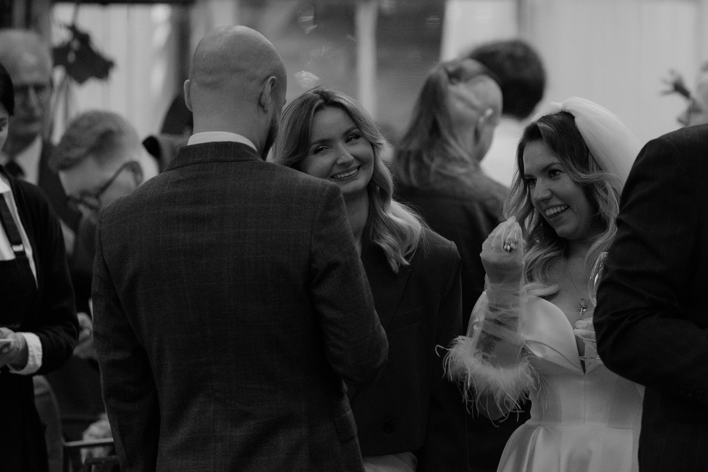 A romantic wedding dance moment captured in black and white as newlyweds spin together surrounded by guests.