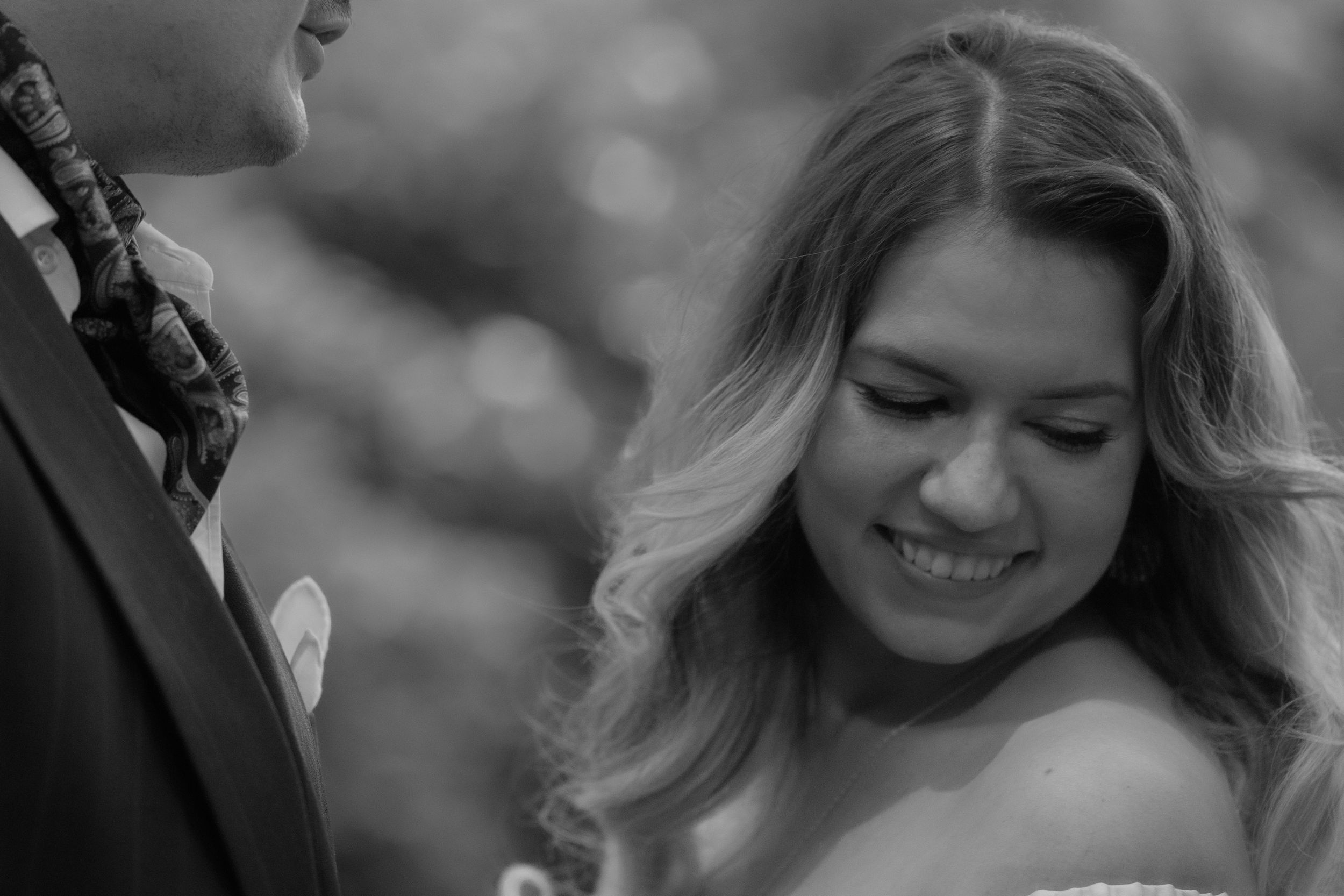 A black and white photograph captures a joyful moment during a wedding ceremony outdoors.