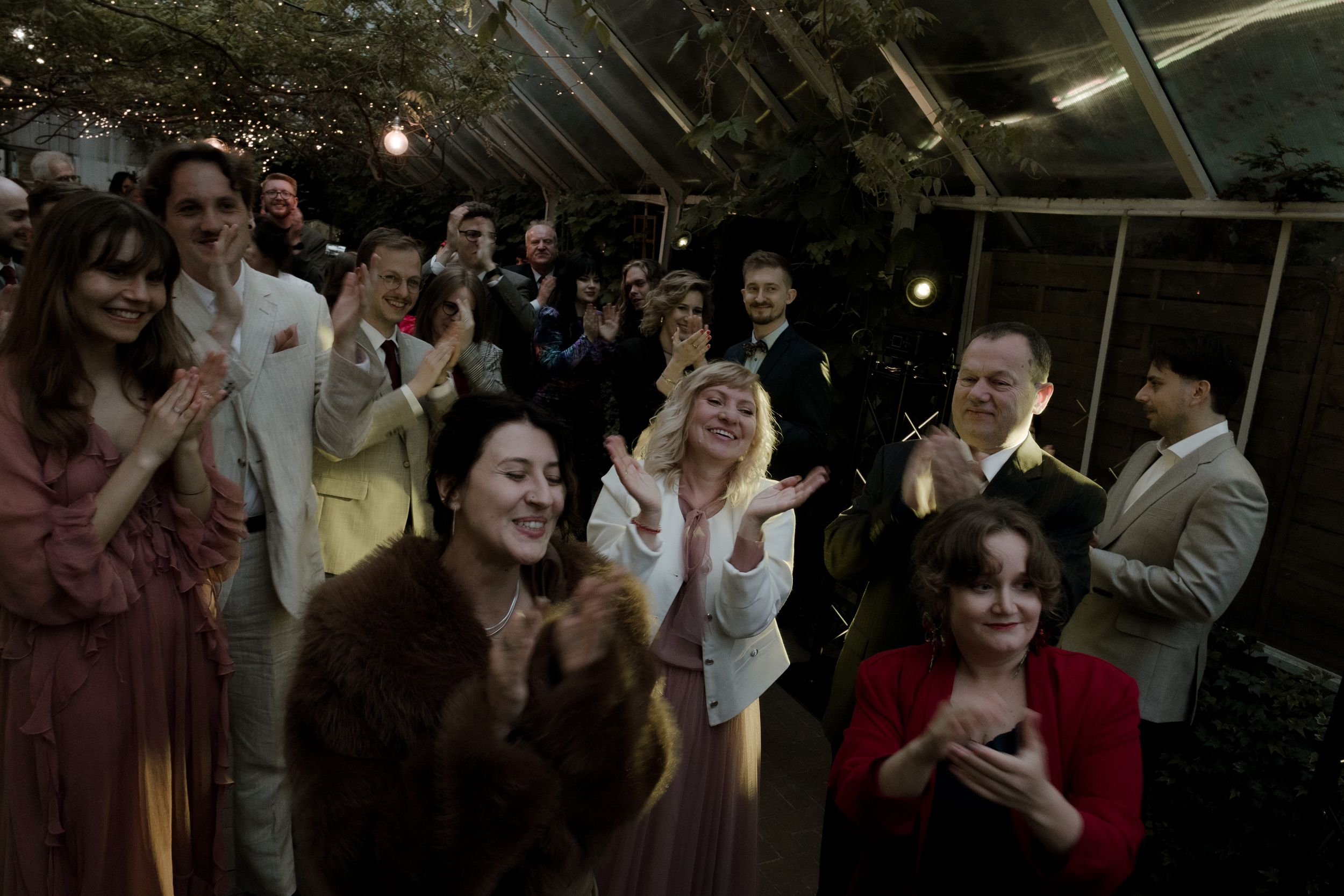 Wedding guests dance and celebrate on a dimly lit dance floor during an evening reception.