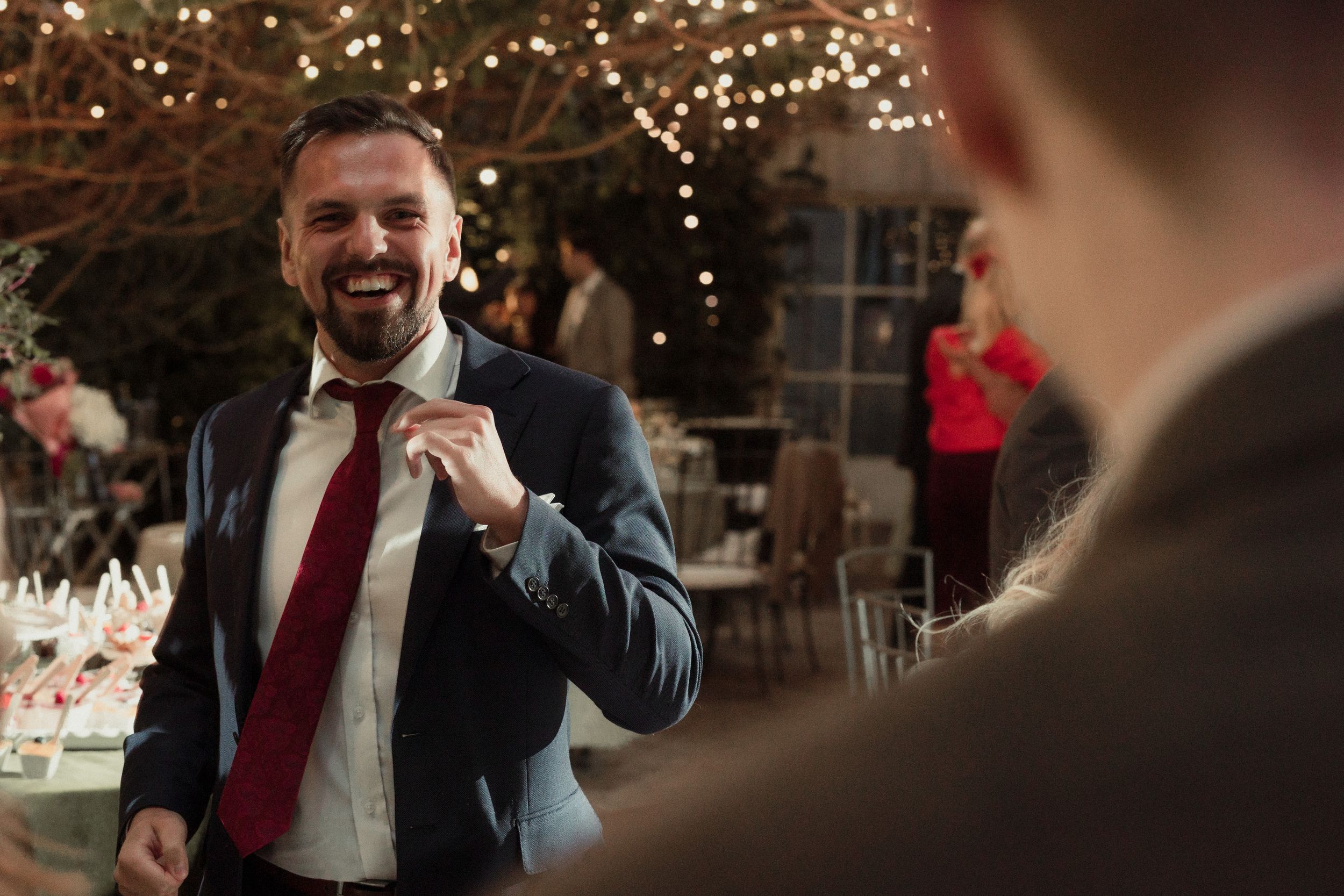 Wedding guests enjoying a festive reception with string lights and decorations creating a warm atmosphere.