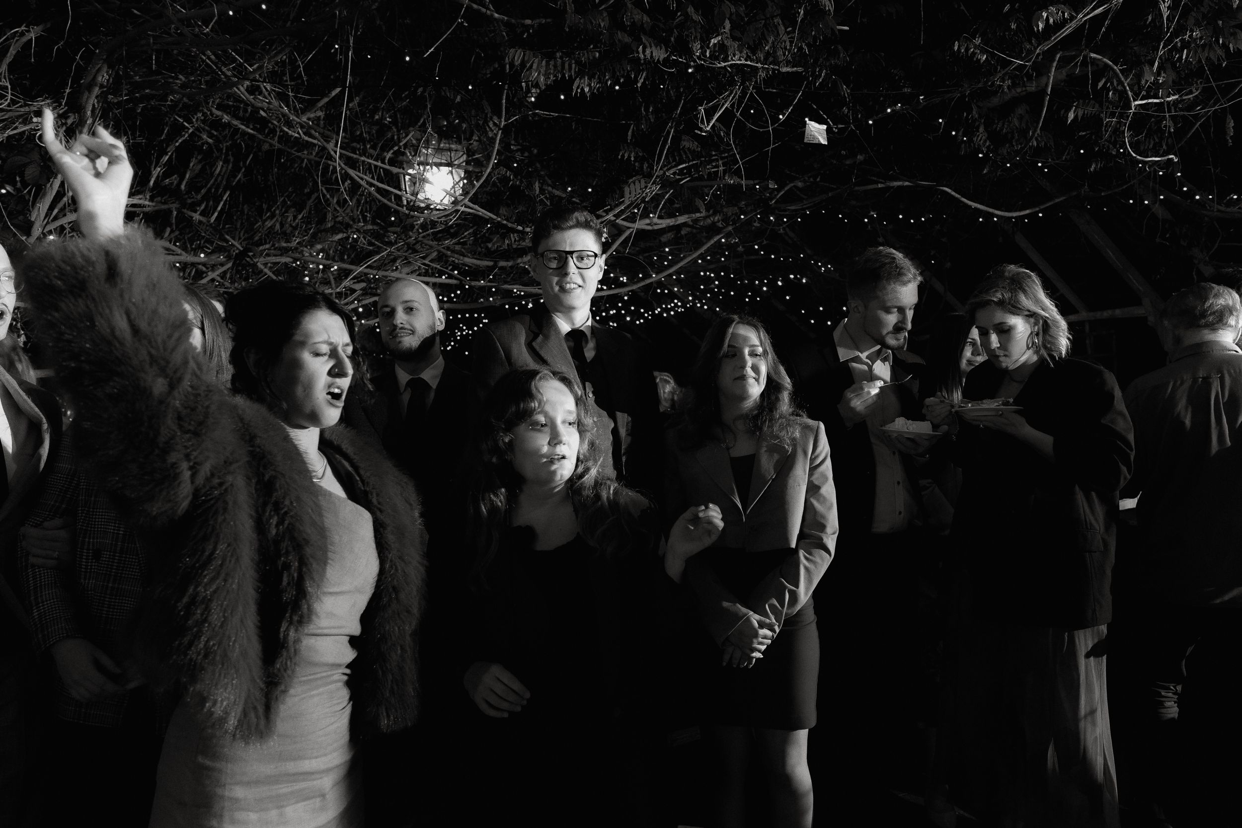 Crowd of party guests dancing together under twinkling lights.