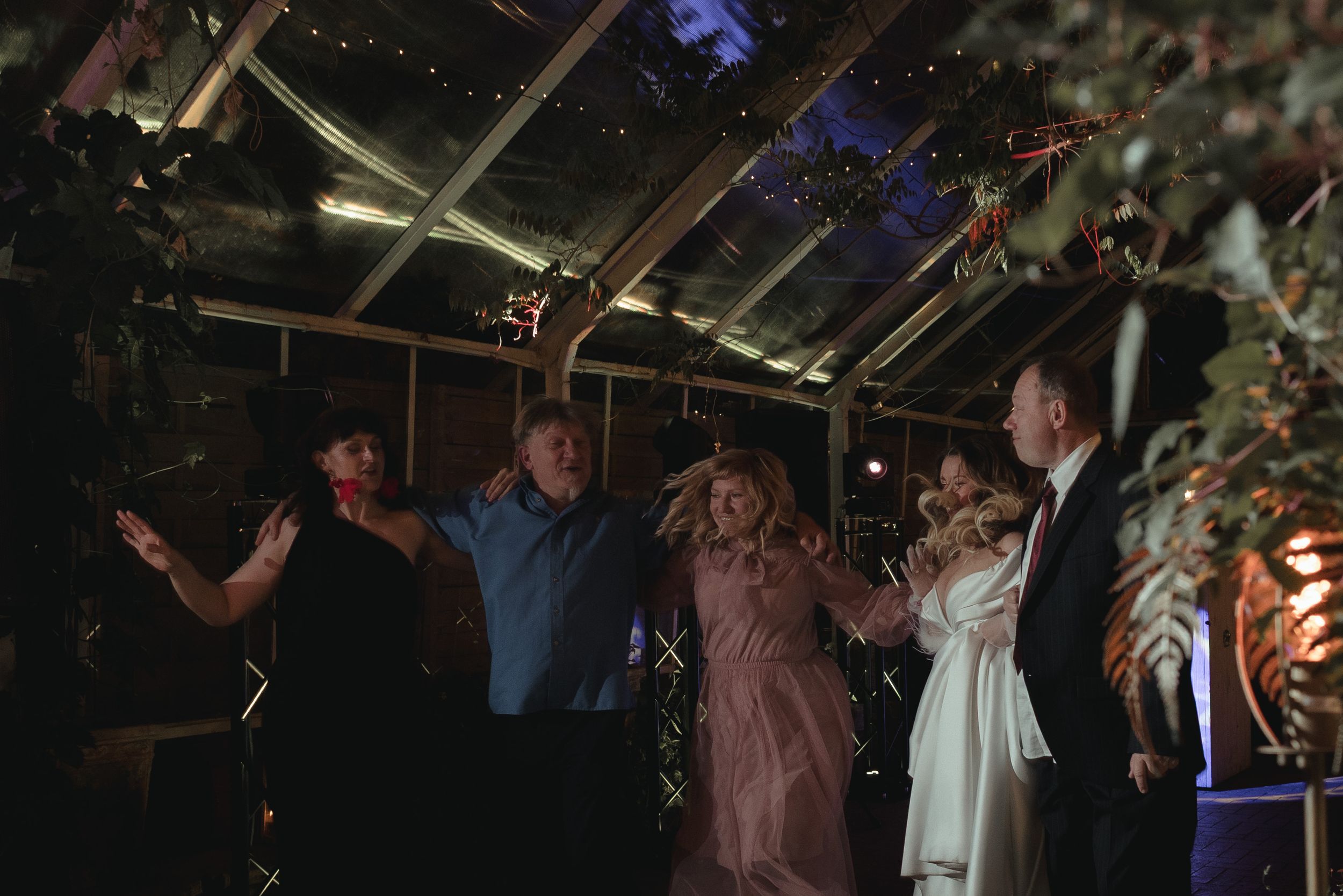 Wedding celebration in a rustic venue with twinkling lights and festive dancing.