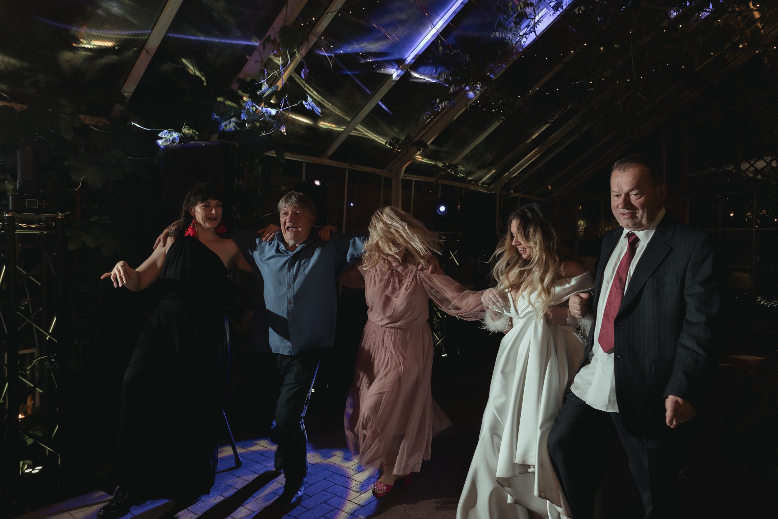 People dancing and celebrating in a dimly lit venue with blue lighting effects.