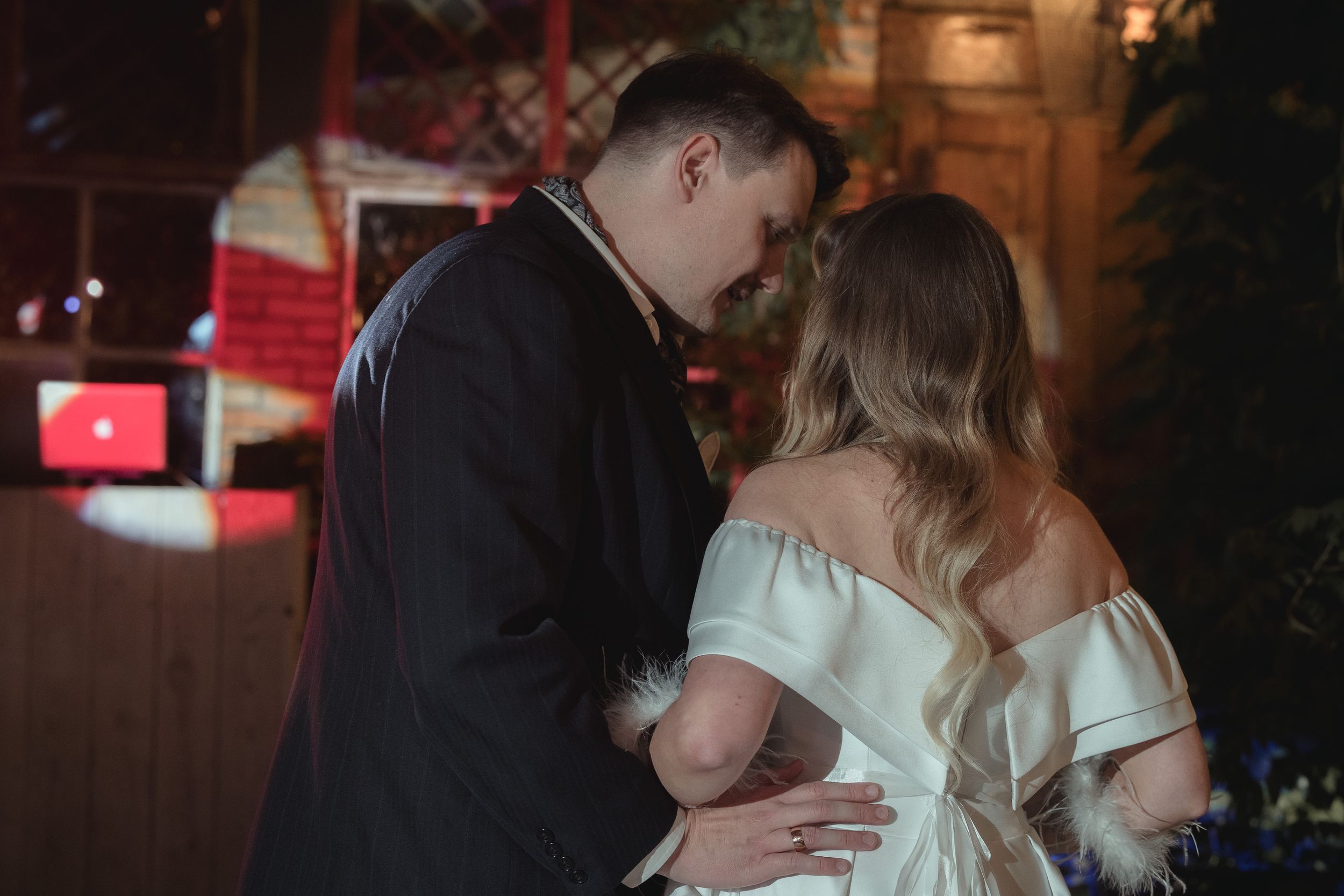 Couples slow dancing in intimate moments at dimly lit wedding reception.