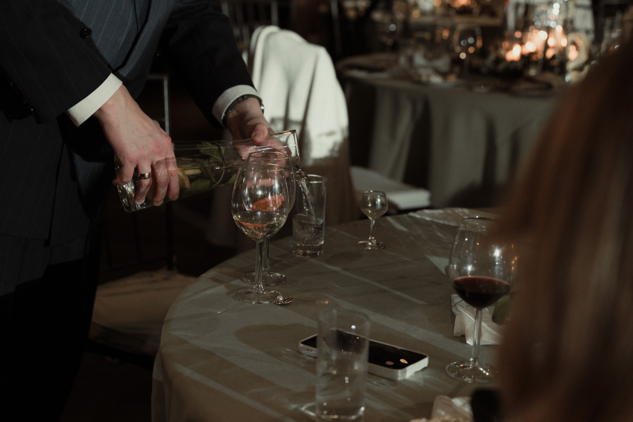 Elegant table settings at a wedding reception with wine glasses and ambient lighting.