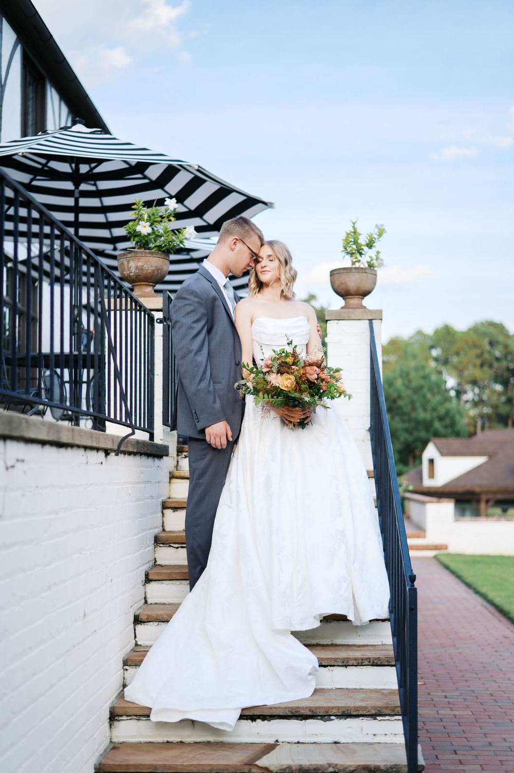 A wedding couple embraces on garden steps in located in Moore County. photographed by Heather Moss Photo in Fayetteville NC