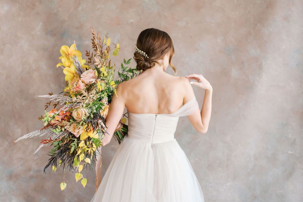 Bride in strapless gown holds colorful autumn bouquet in a studio. Photograph by Fayetteville NC wedding photographer